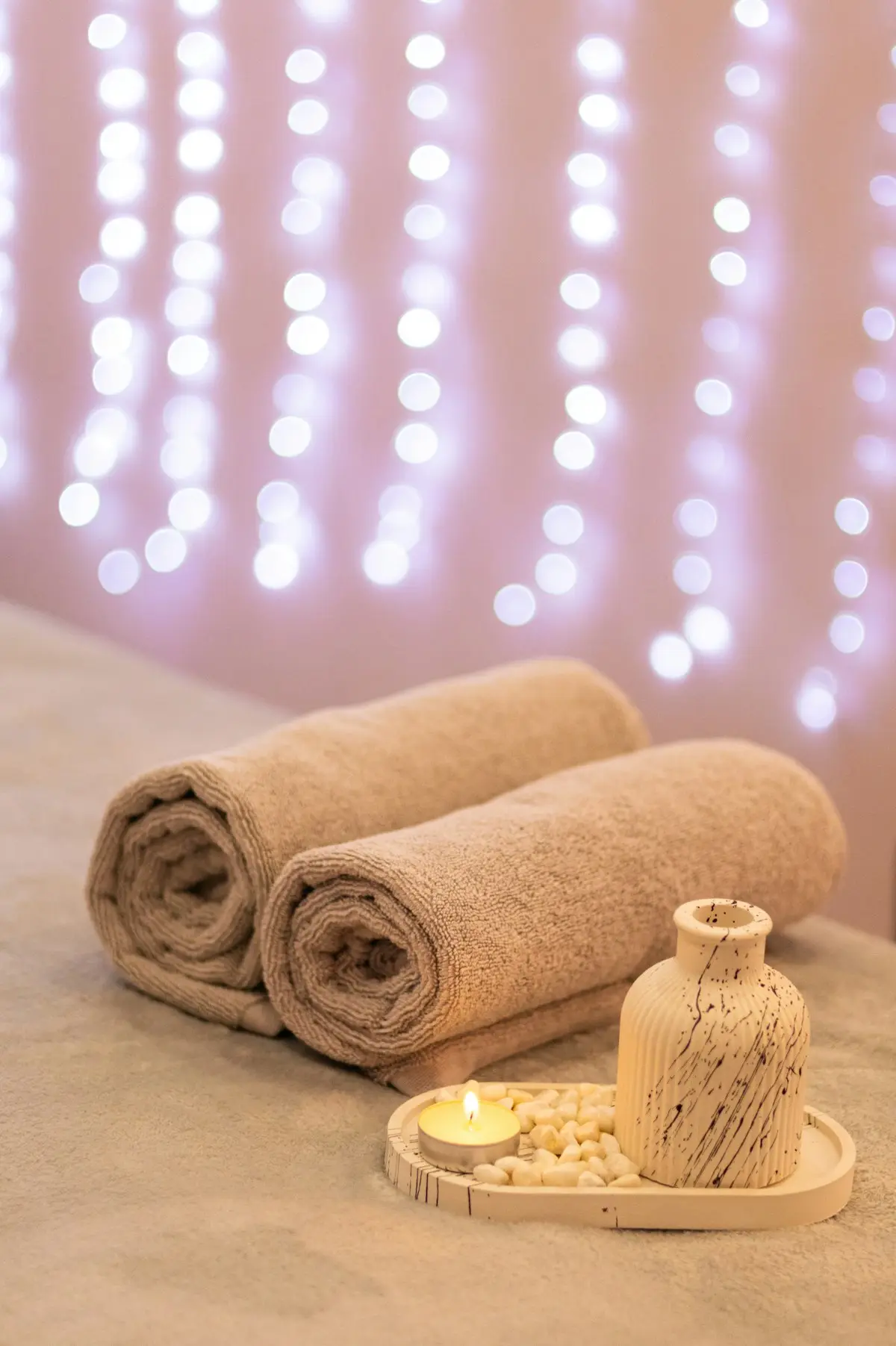 Rolled spa towels beside a candle